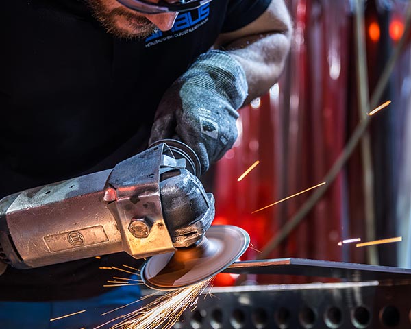 Mitarbeitender von QABUS Metallbau bei der Bearbeitung eines Bauteils